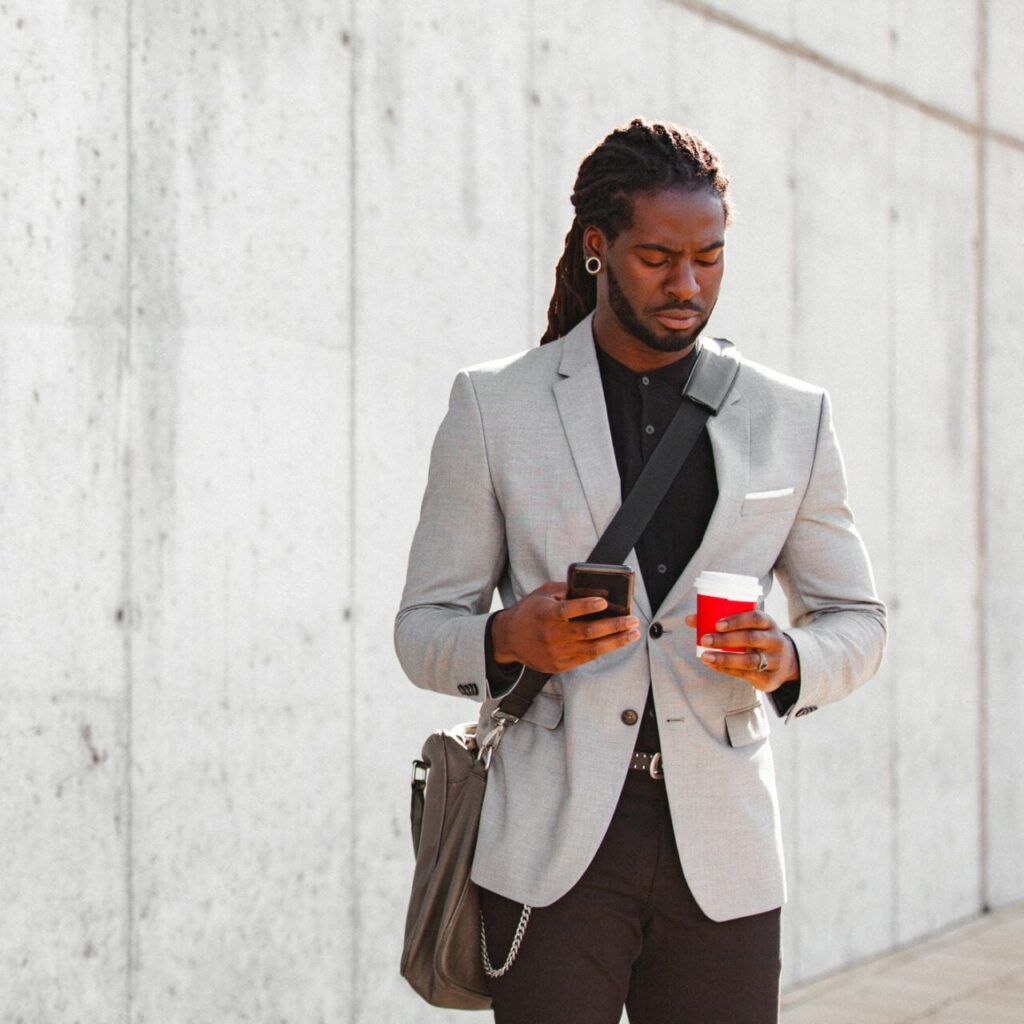 Young man using a smartphone whilst holding a coffee