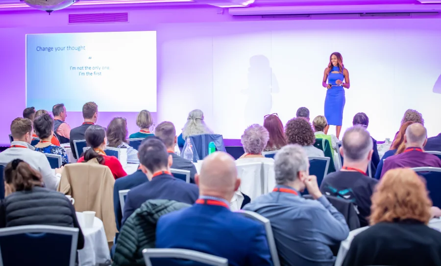Caroline Flanagan on stage speaking to a large audience at an international conference on inclusive leadership