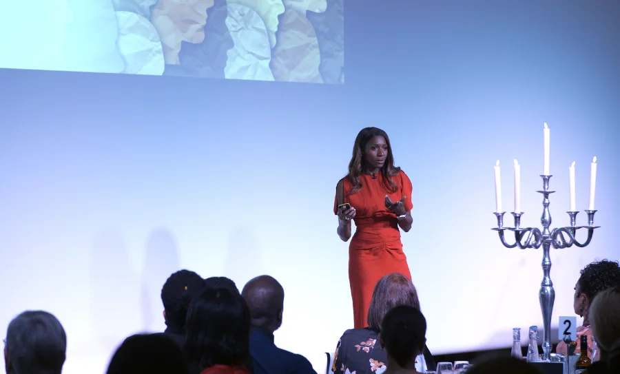 Caroline Flanagan on stage in a red dress delivering a keynote at a law firm event